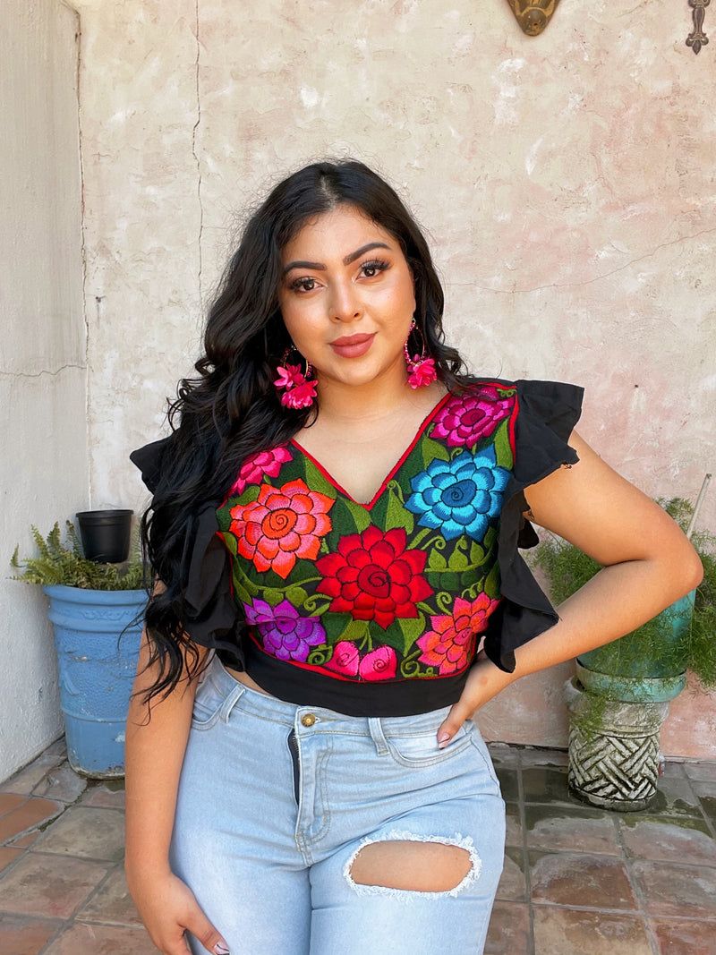 Modelo con top negro bordado y jeans