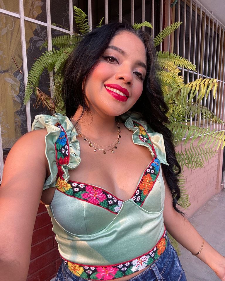 Mujer vistiendo un top verde con bordado de flores